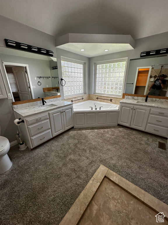 Bathroom with a bath, vanity, toilet, and lofted ceiling