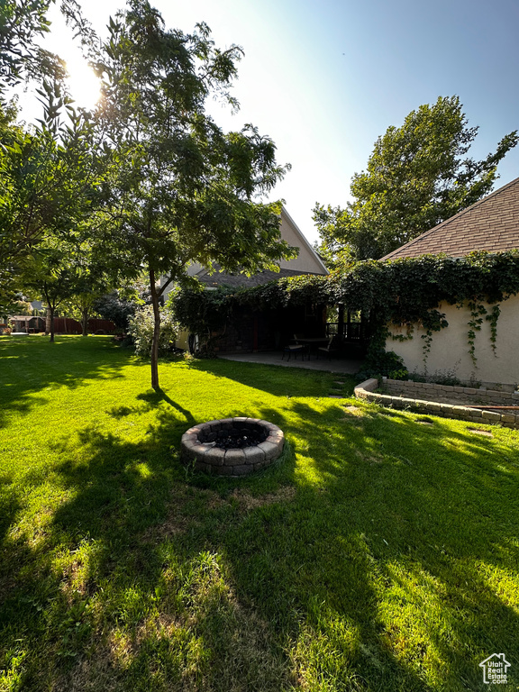 View of grassy yard with an outdoor fire pit and a patio