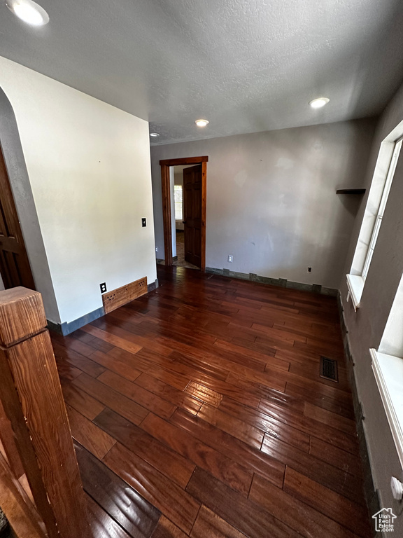 Spare room with wood-type flooring, arched walkways, baseboards, recessed lighting, and a textured ceiling