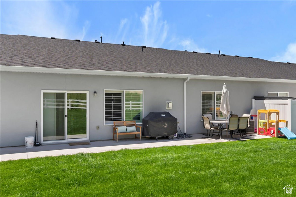 Back of property featuring a patio, roof with shingles, stucco siding, and a lawn