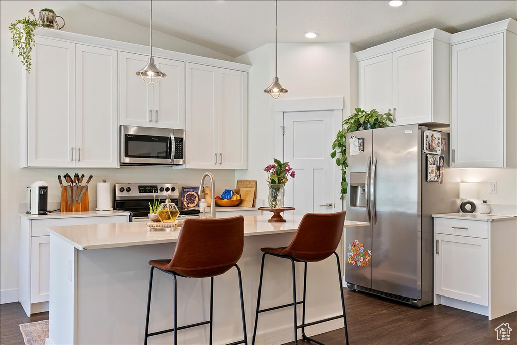Kitchen featuring stainless steel appliances, dark wood-style flooring, recessed lighting, white cabinetry, and lofted ceiling