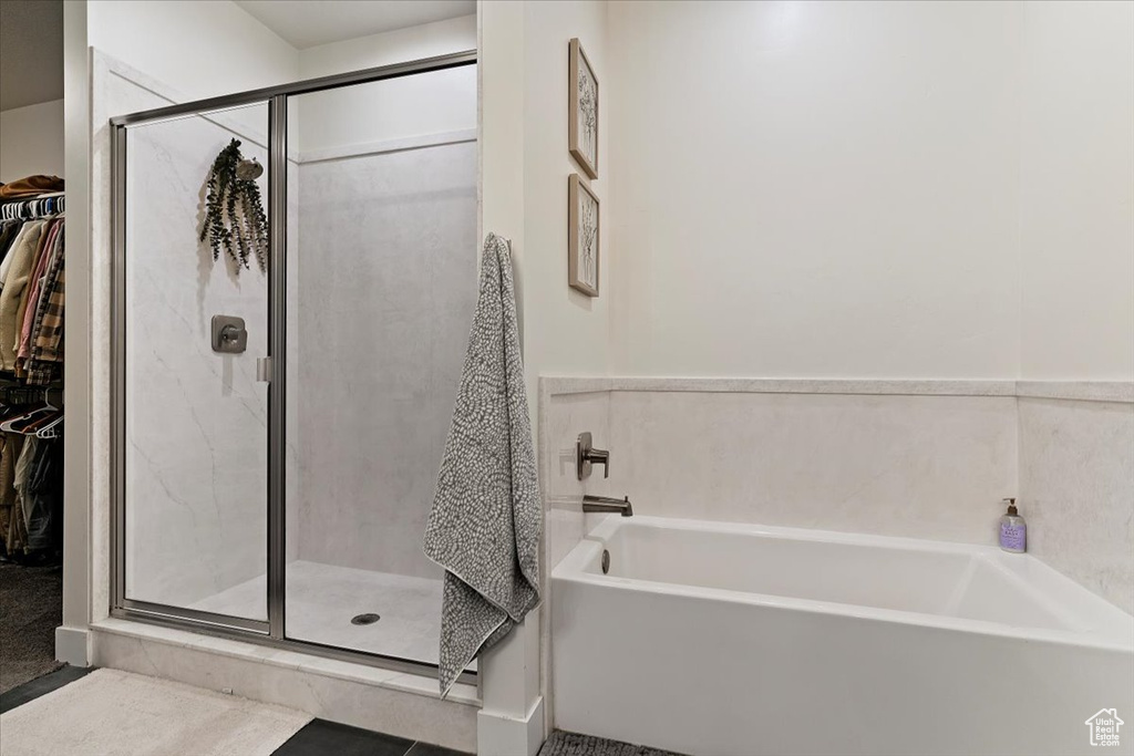 Full bathroom with a stall shower, a bath, and a spacious closet