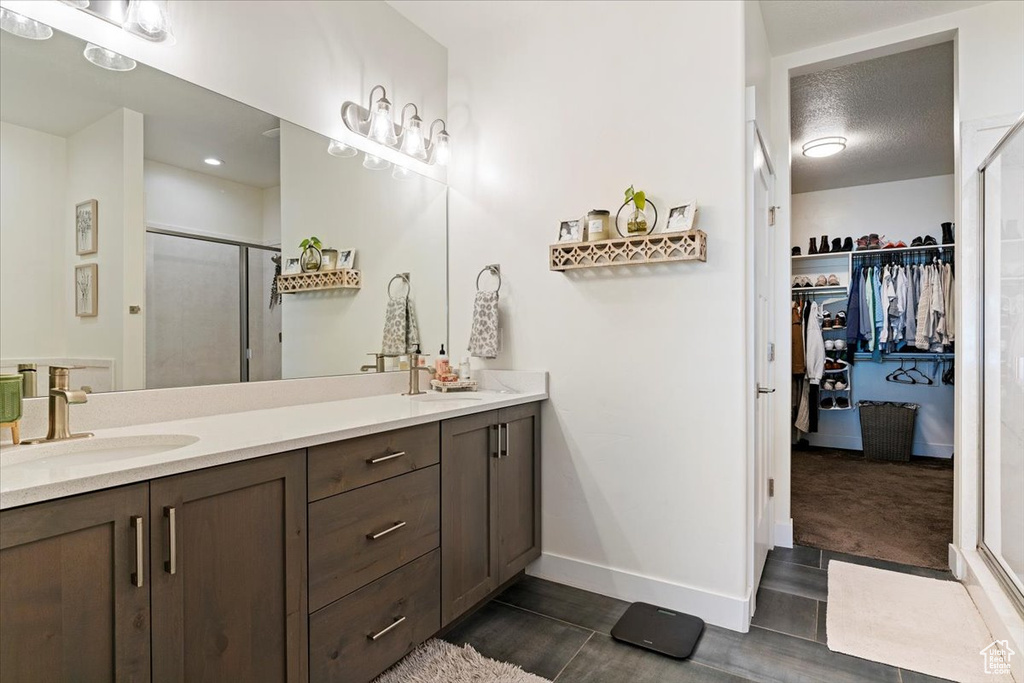 Full bathroom with a shower stall, double vanity, baseboards, wood finished floors, and a spacious closet