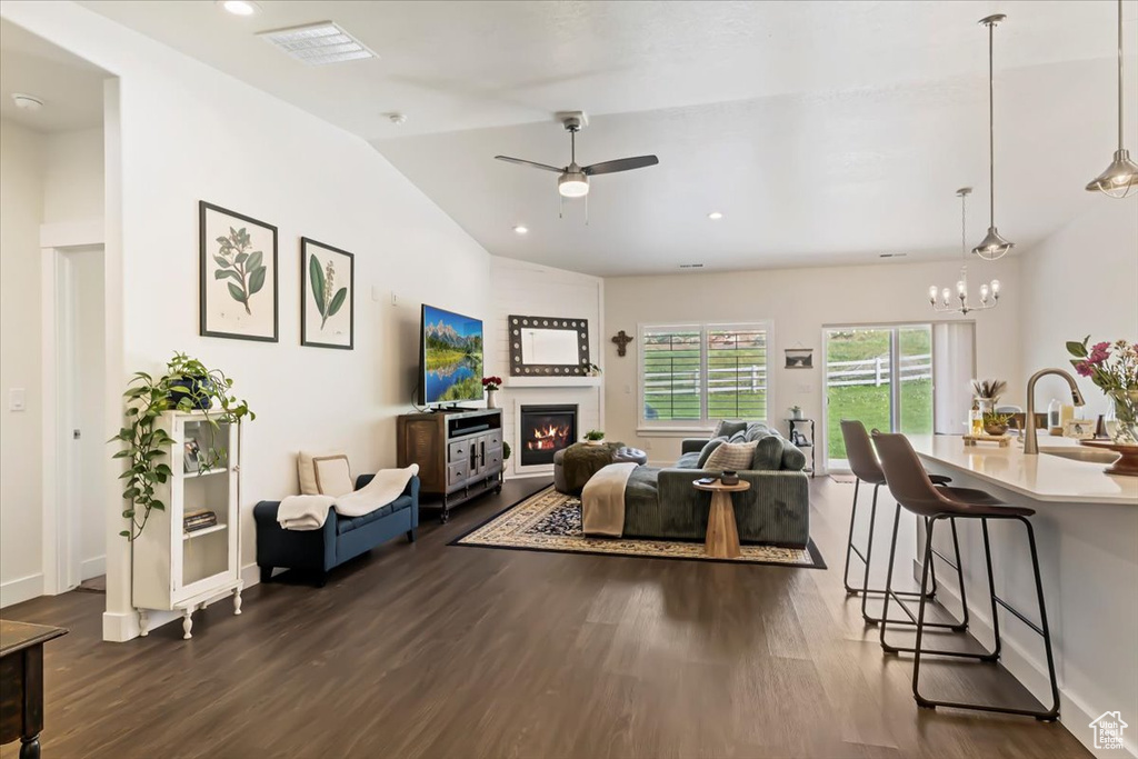 Living area with dark wood-style flooring, a ceiling fan, lofted ceiling, a glass covered fireplace, and recessed lighting