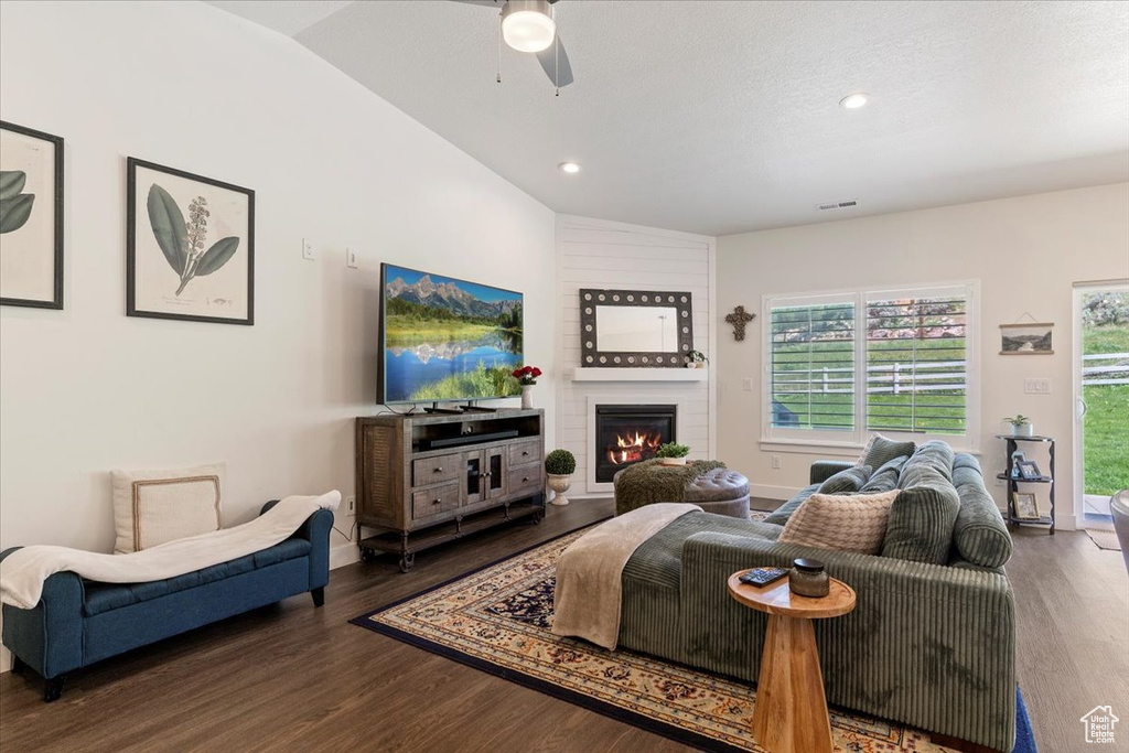 Living room featuring wood finished floors, lofted ceiling, ceiling fan, a fireplace, and recessed lighting