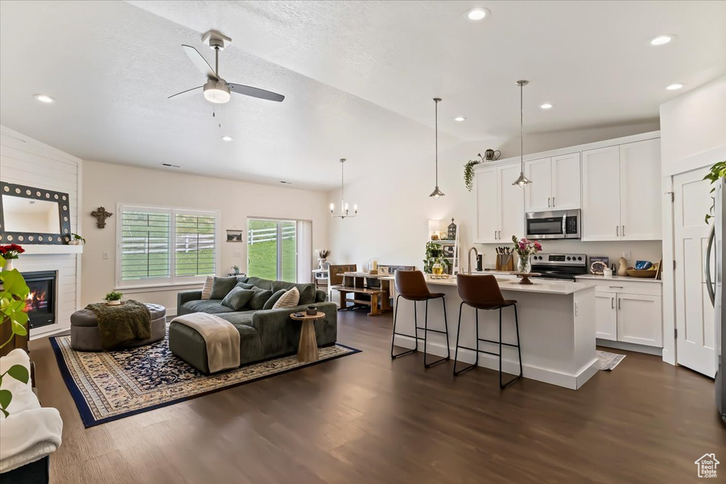 Living area featuring ceiling fan, dark wood finished floors, lofted ceiling, a large fireplace, and recessed lighting
