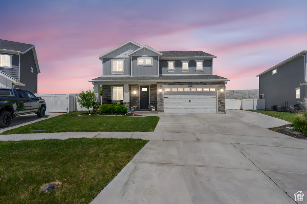 View of front of home featuring a gate, concrete driveway, a garage, stone siding, and board and batten siding