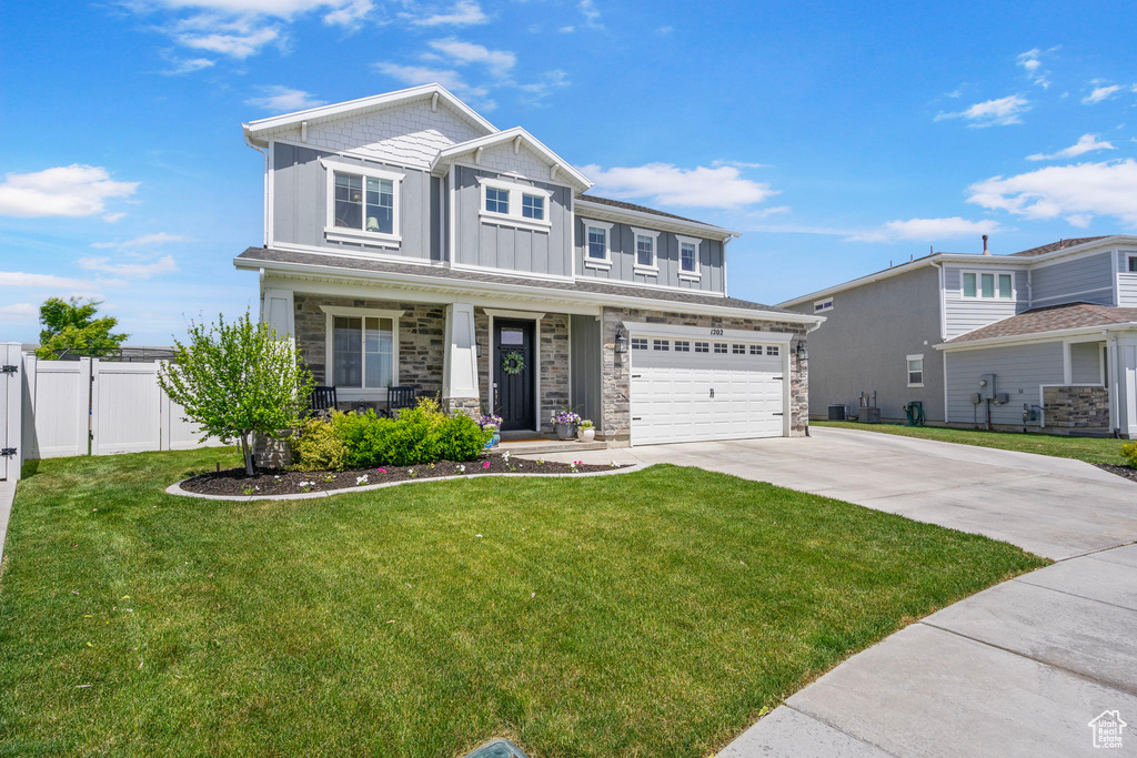 Craftsman house with board and batten siding, stone siding, driveway, a garage, and a porch
