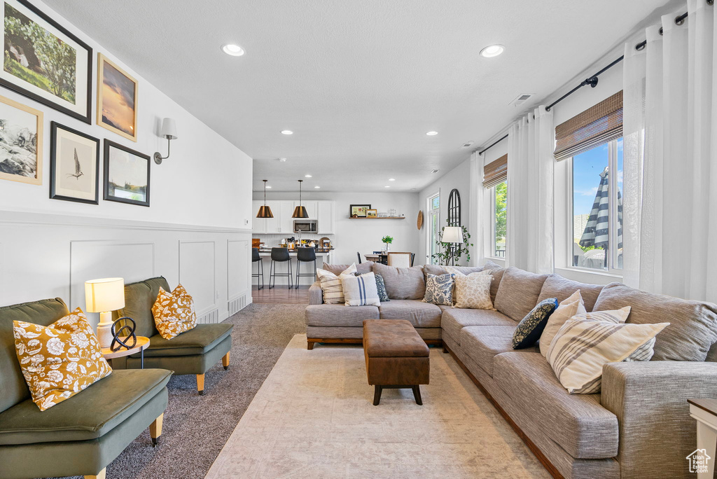 Living room with recessed lighting, light carpet, a decorative wall, and a wainscoted wall
