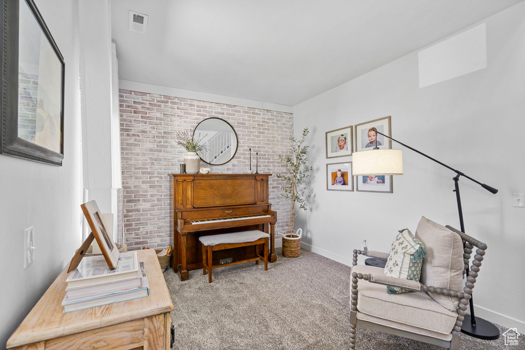 Sitting room featuring carpet flooring, brick wall, and baseboards