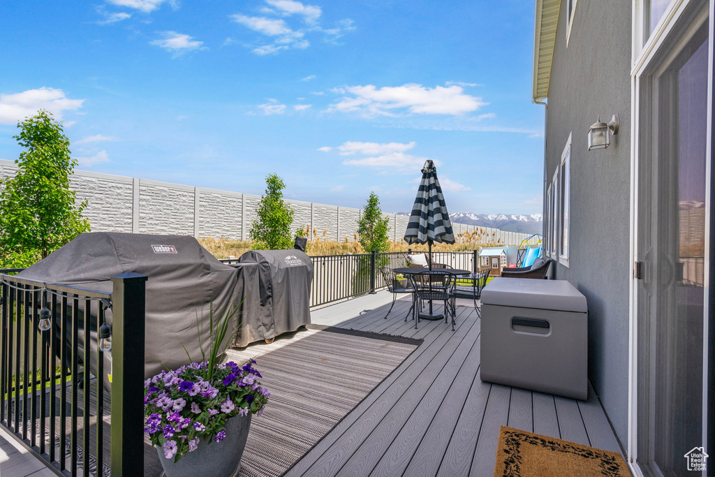 Deck featuring outdoor dining area, a water view, and a grill