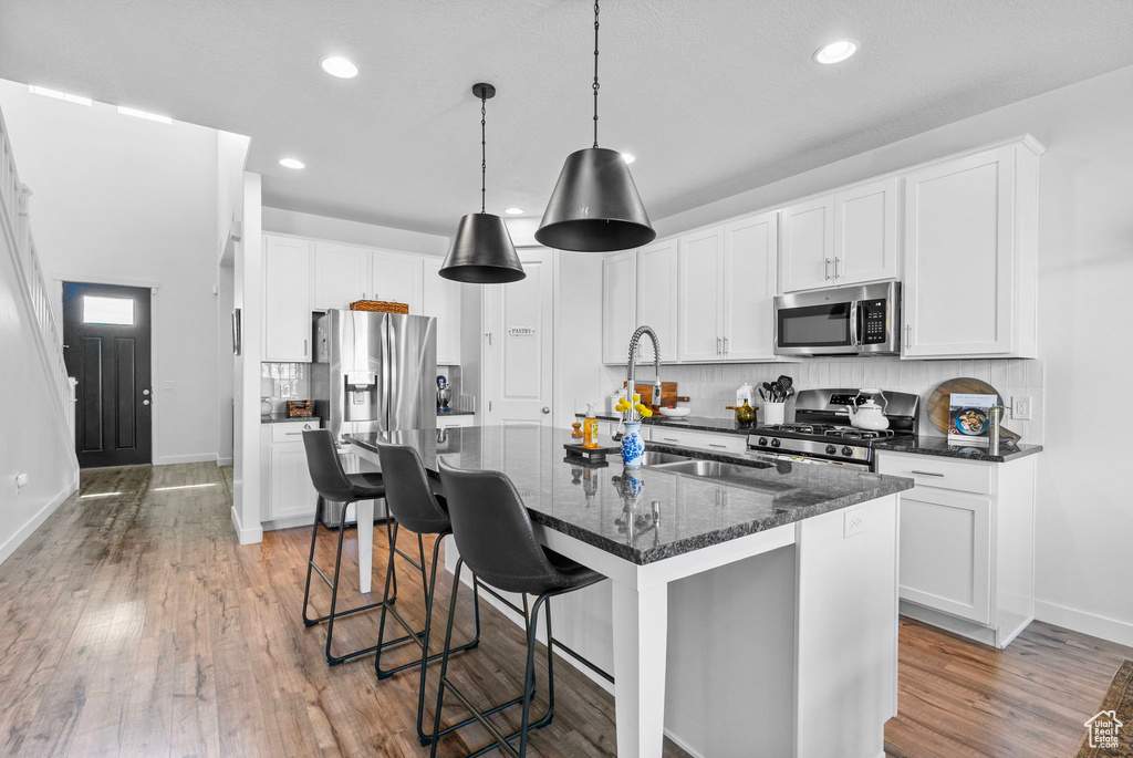 Kitchen with stainless steel appliances, backsplash, baseboards, recessed lighting, and light wood finished floors
