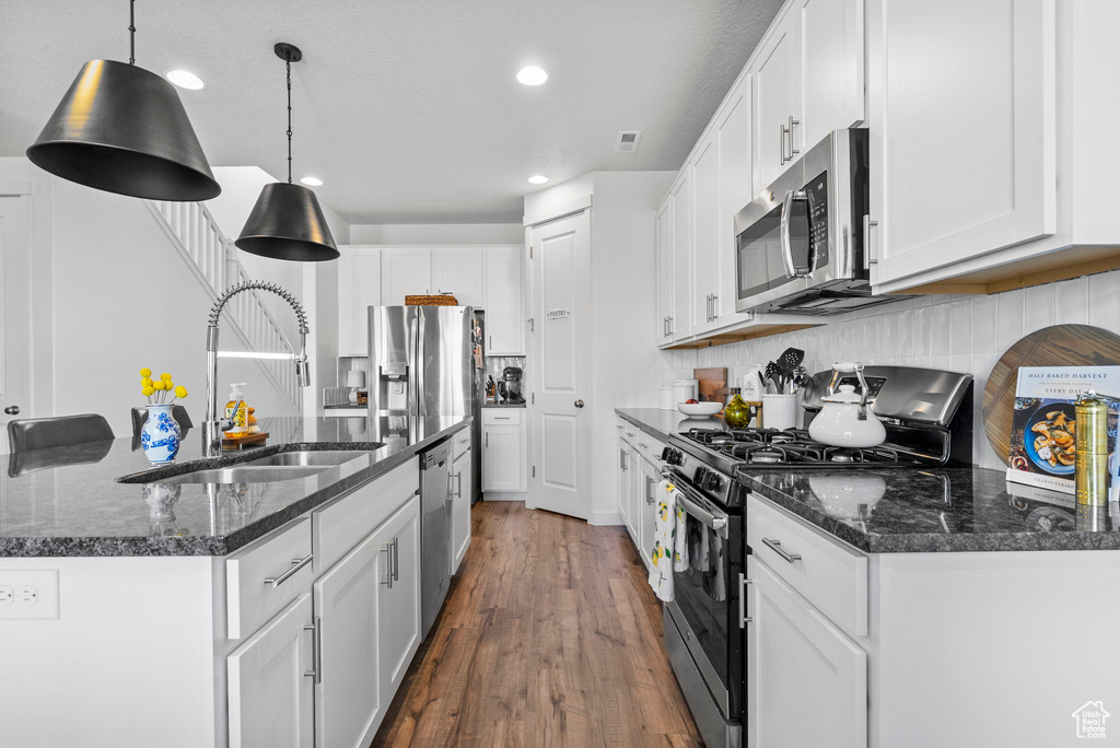 Kitchen with appliances with stainless steel finishes, a sink, white cabinets, and recessed lighting