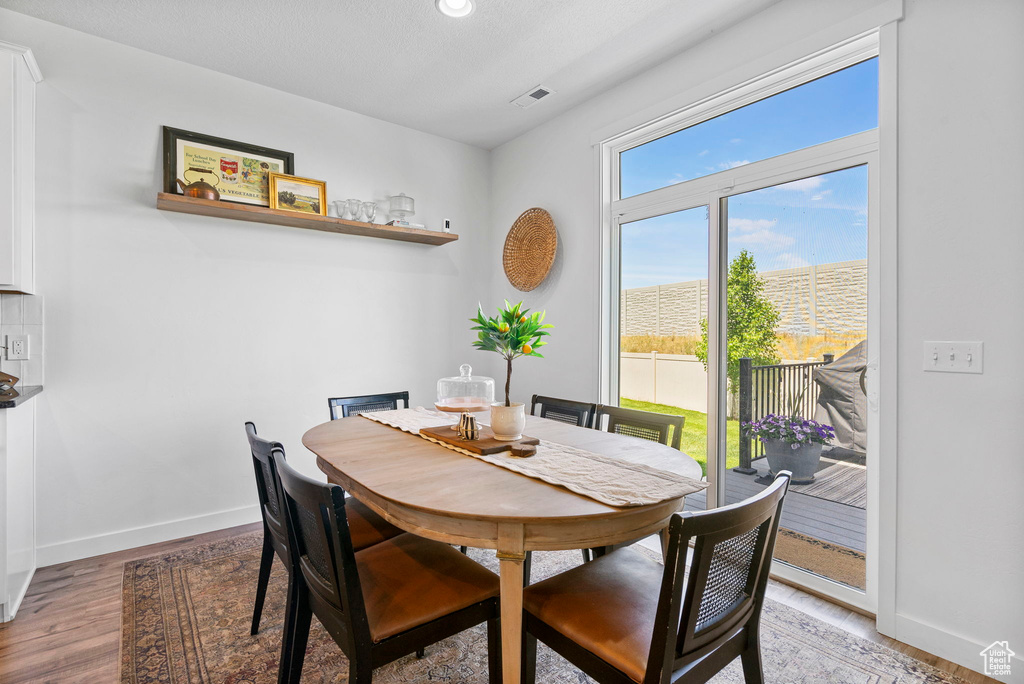 Dining room with light wood finished floors, baseboards, and recessed lighting