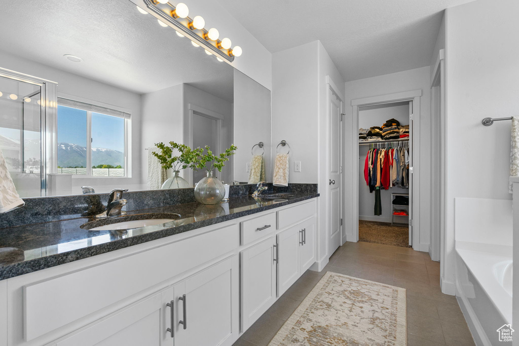 Bathroom with double vanity, a bath, a spacious closet, tile patterned flooring, and a shower with door