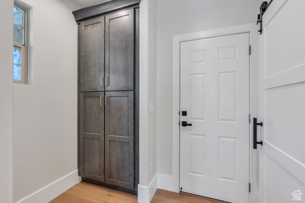 Doorway with light wood-type flooring, baseboards, and a barn door