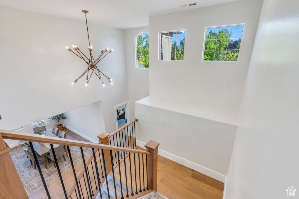 Staircase featuring a chandelier, wood finished floors, and baseboards
