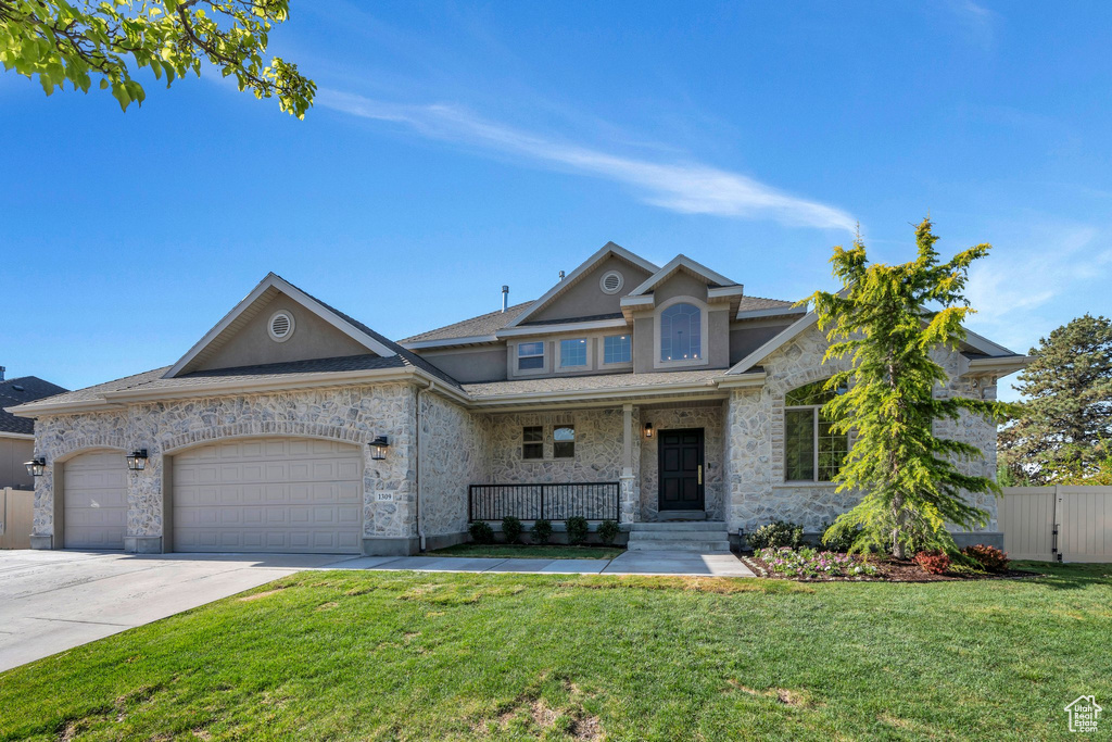 View of front of property featuring a porch, a garage, stone siding, driveway, and roof with shingles