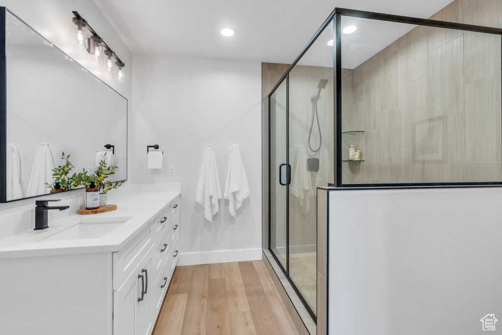 Bathroom featuring recessed lighting, vanity, a stall shower, wood finished floors, and baseboards
