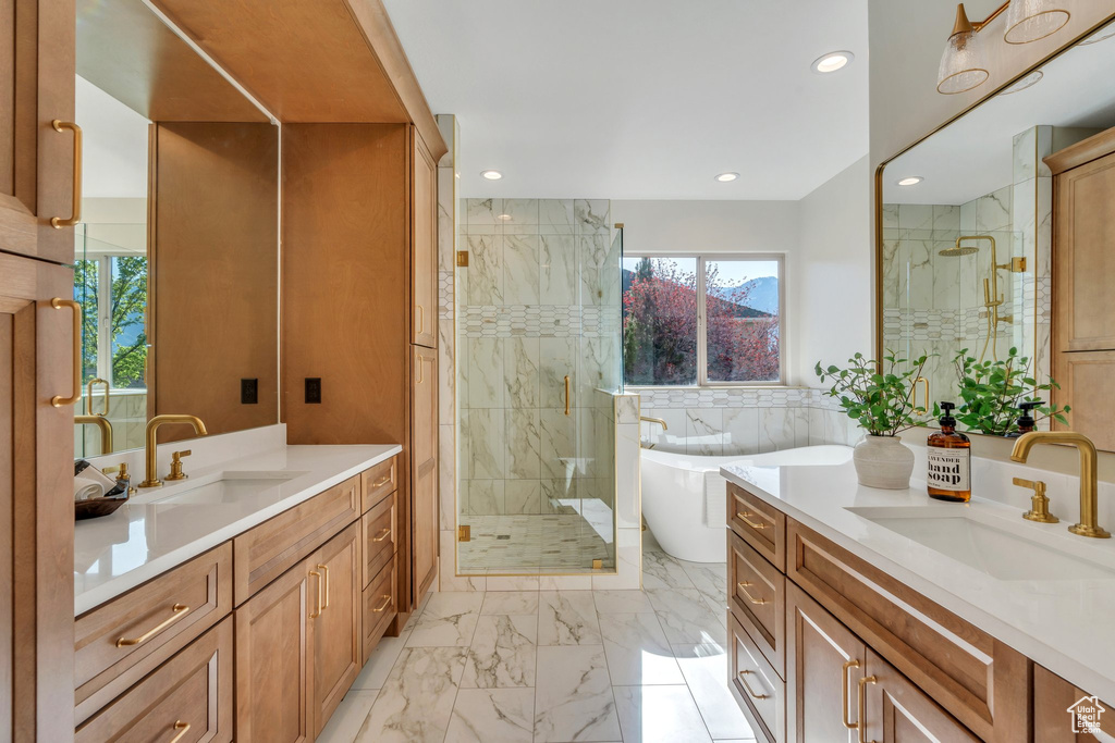 Full bathroom with a stall shower, marble finish flooring, a freestanding tub, two vanities, and recessed lighting