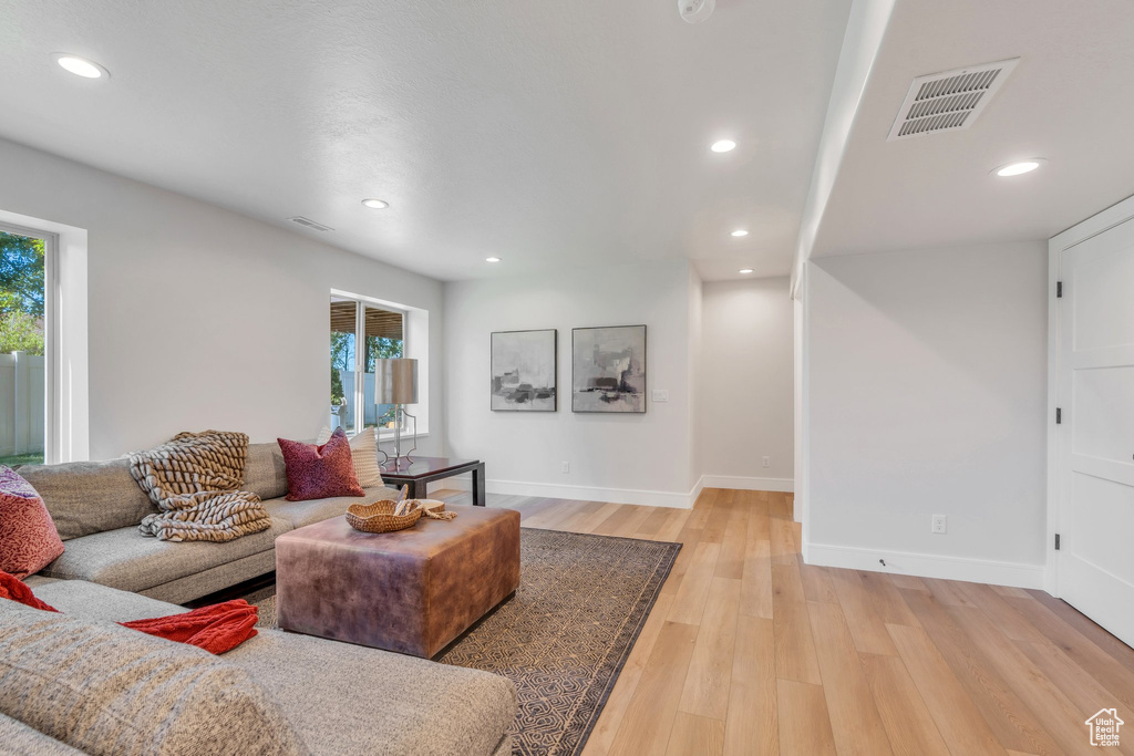 Living room featuring plenty of natural light, baseboards, light wood finished floors, and recessed lighting