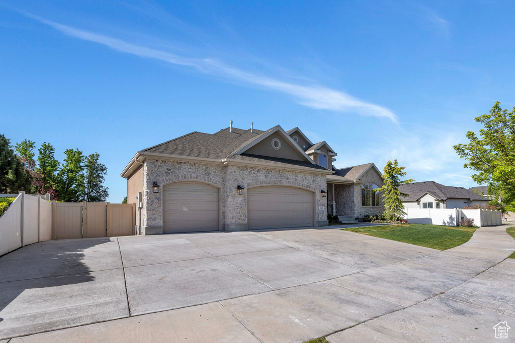 French country home featuring concrete driveway, a garage, a gate, stone siding, and a shingled roof