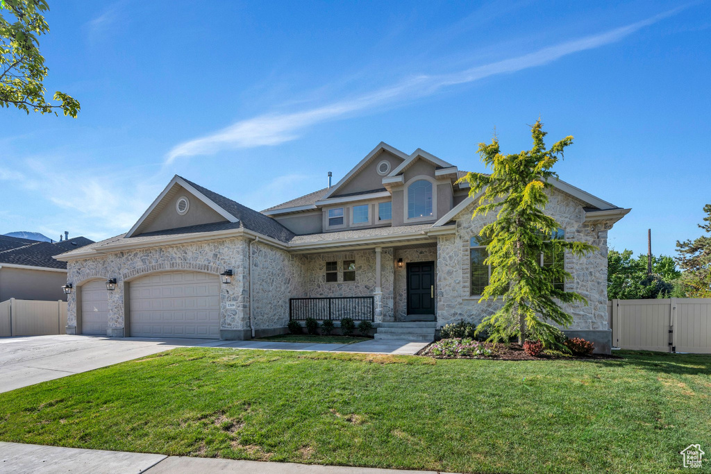 View of front of home featuring covered porch, stone siding, an attached garage, and driveway