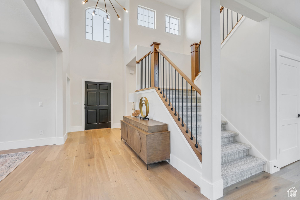 Entryway featuring a towering ceiling, wood finished floors, stairs, and healthy amount of natural light