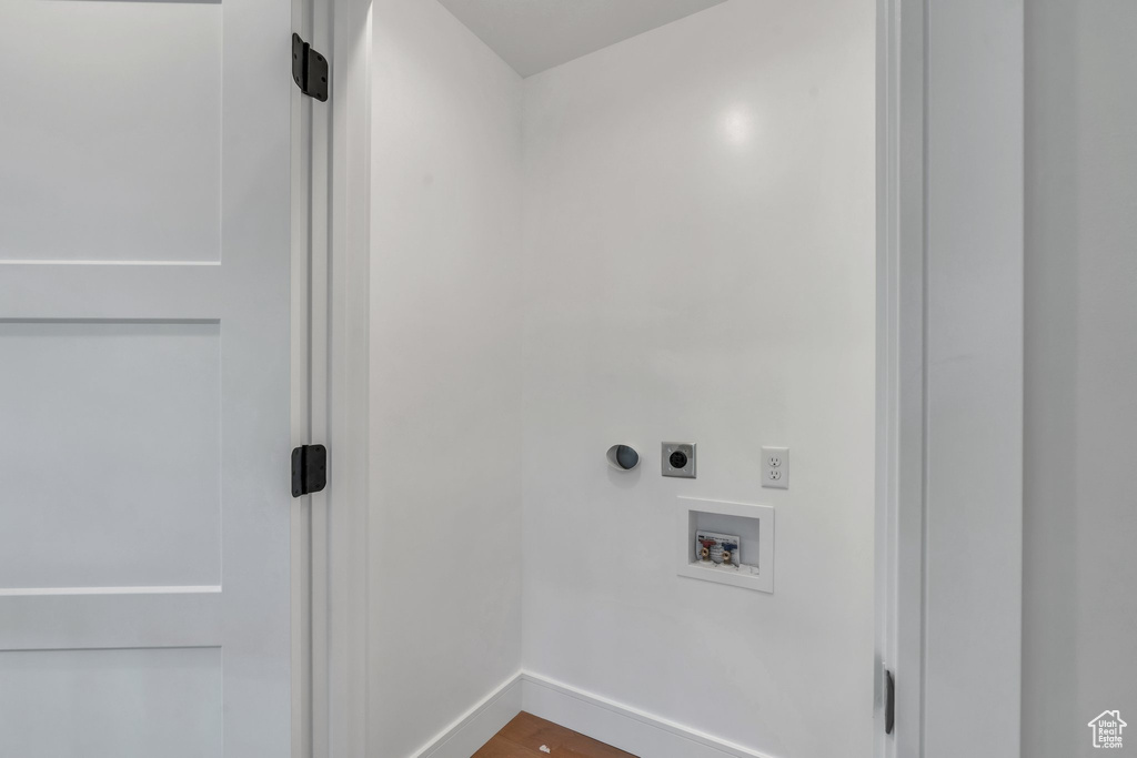 Clothes washing area featuring hookup for an electric dryer, hookup for a washing machine, baseboards, and wood finished floors