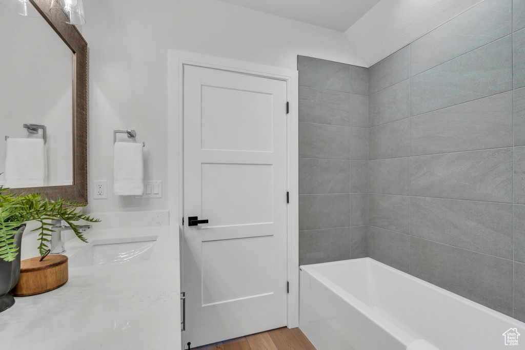 Full bath featuring a bath, vanity, and wood finished floors
