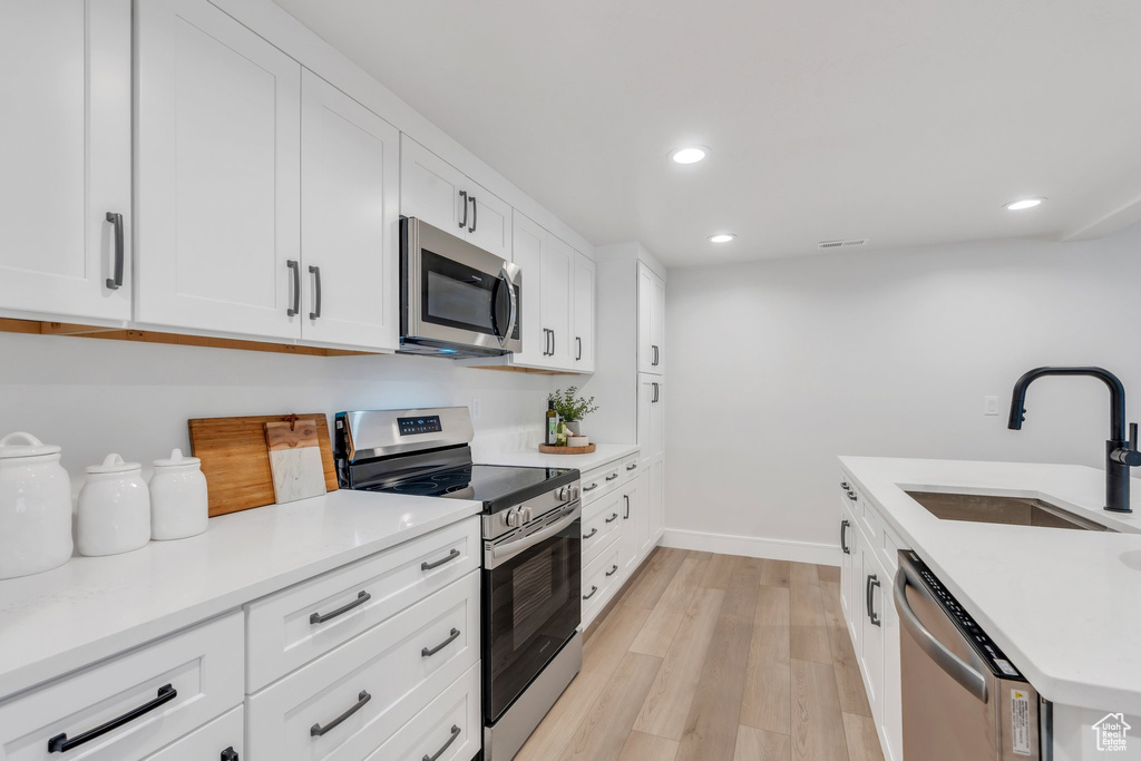 Kitchen featuring stainless steel appliances, a sink, light wood-style floors, recessed lighting, and baseboards