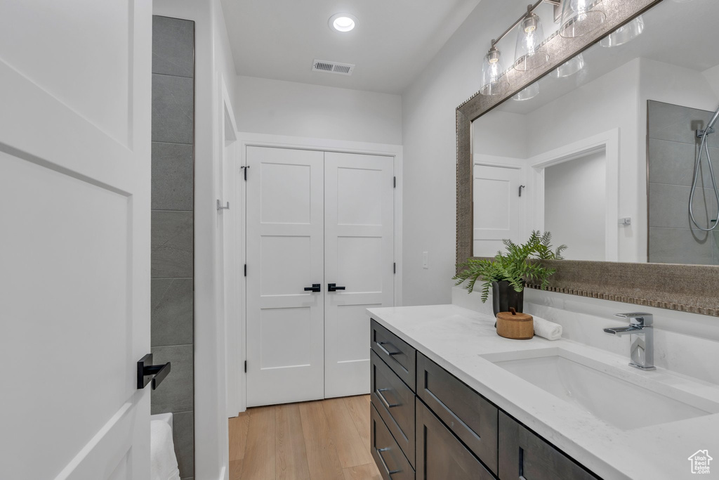 Bathroom featuring vanity, wood finished floors, a shower, and recessed lighting