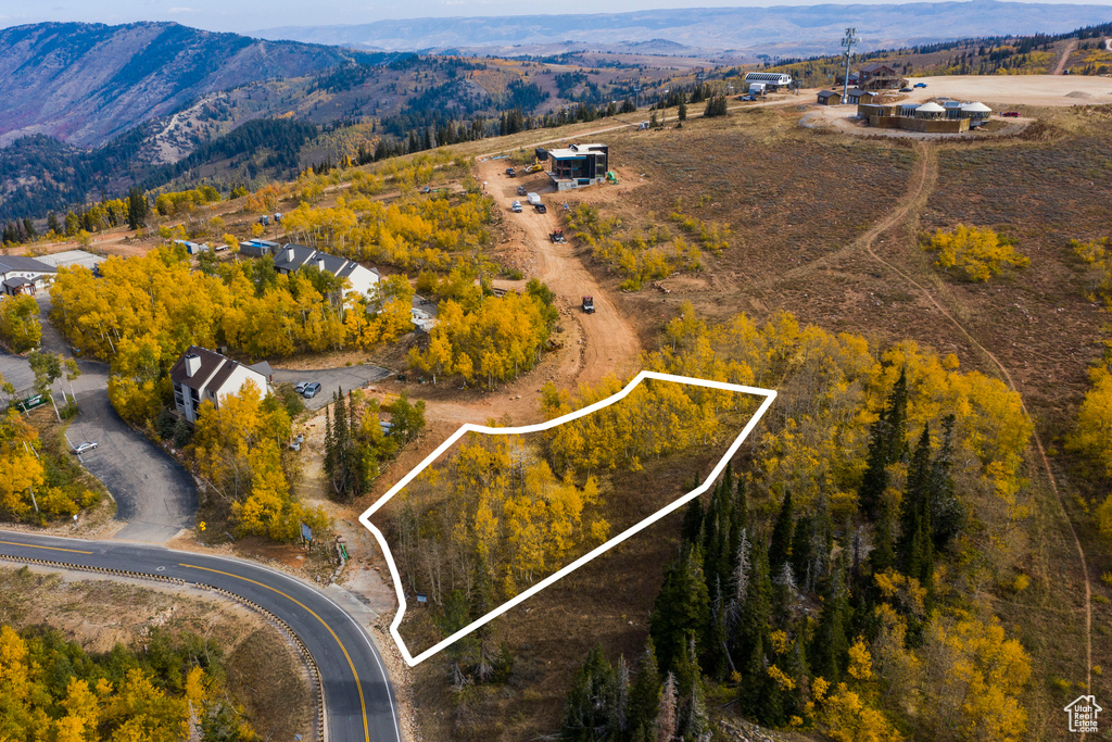 Aerial view of property and surrounding area featuring property boundaries highlighted and a mountainous background