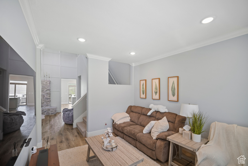 Living room featuring ornamental molding, stairway, light wood finished floors, recessed lighting, and baseboards