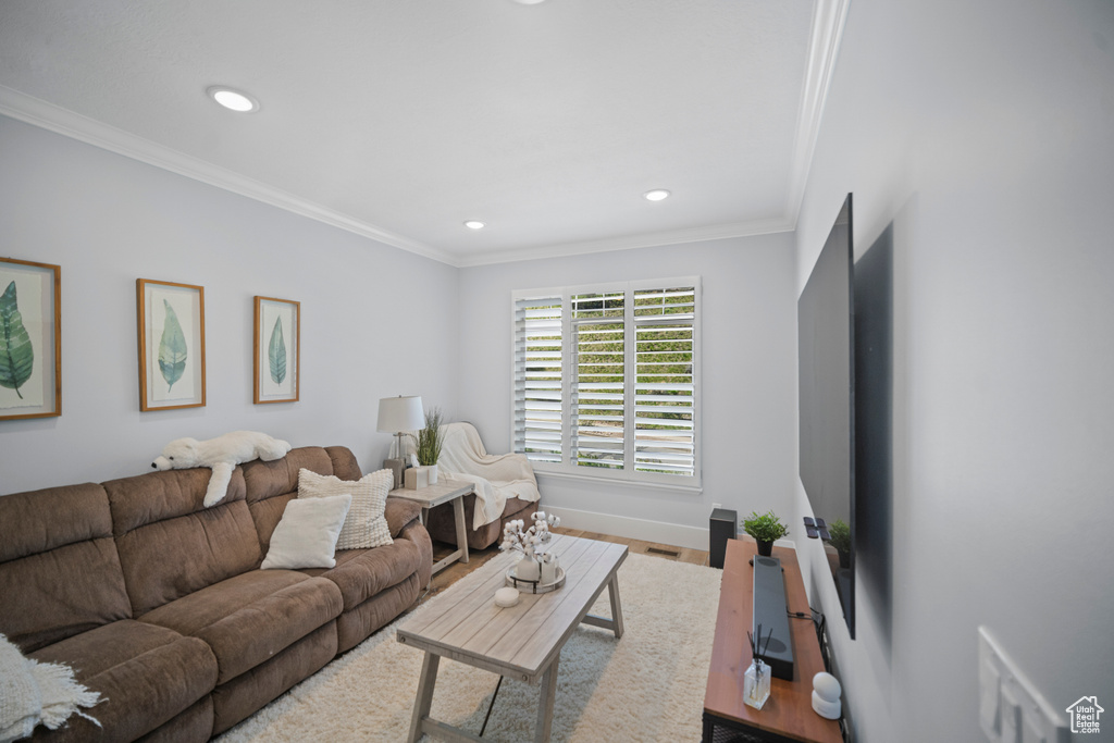 Living room featuring recessed lighting, crown molding, baseboards, and wood finished floors