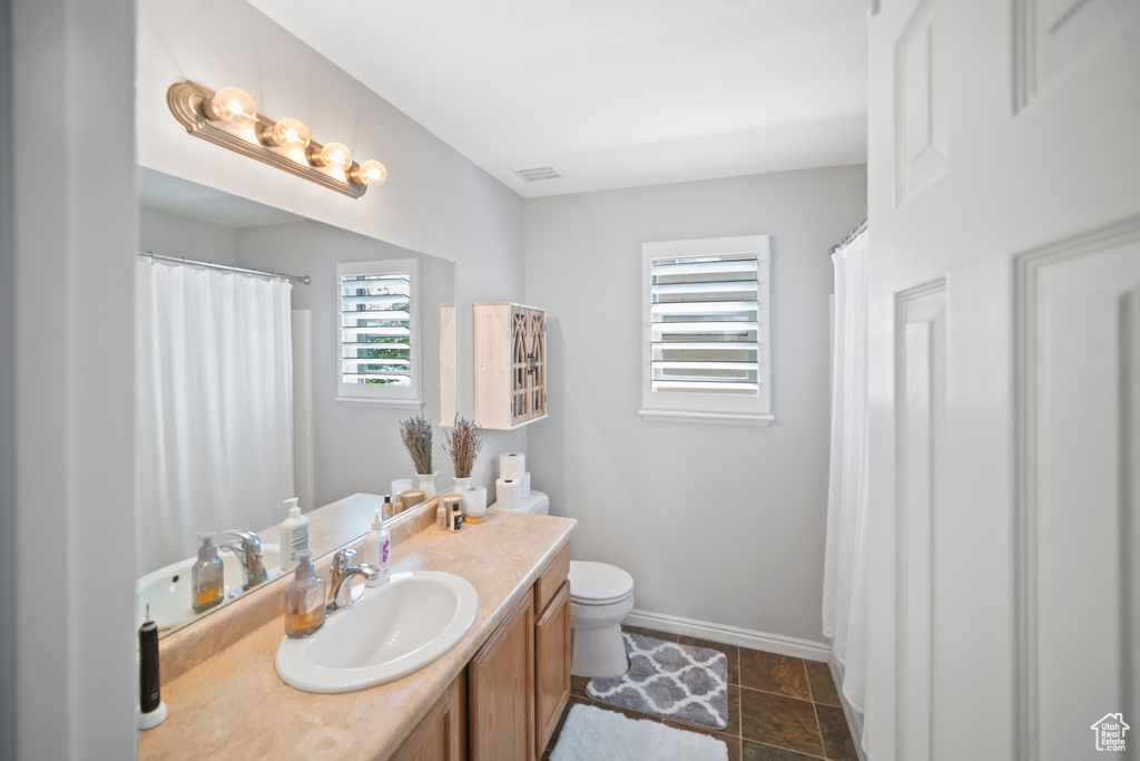 Full bath with toilet, vanity, and baseboards
