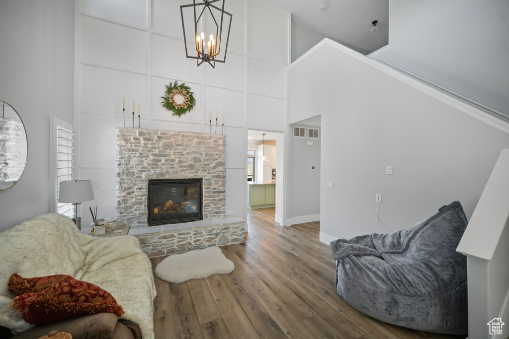 Living area with a towering ceiling, wood finished floors, a chandelier, a fireplace, and baseboards