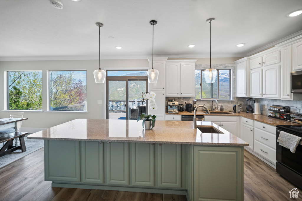 Kitchen featuring electric range, plenty of natural light, crown molding, white cabinets, and recessed lighting