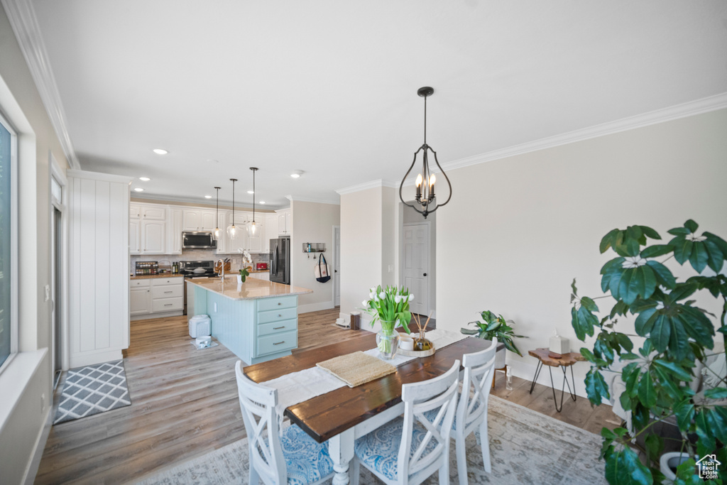 Dining room featuring ornamental molding, light wood finished floors, recessed lighting, a chandelier, and baseboards