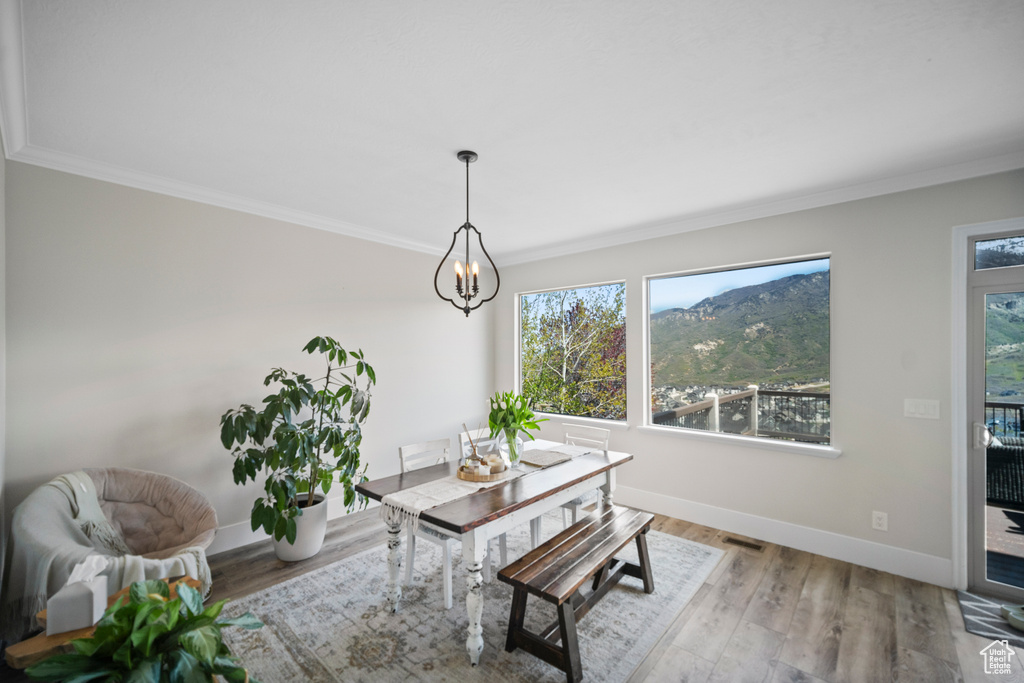 Dining area featuring a chandelier, ornamental molding, baseboards, and wood finished floors