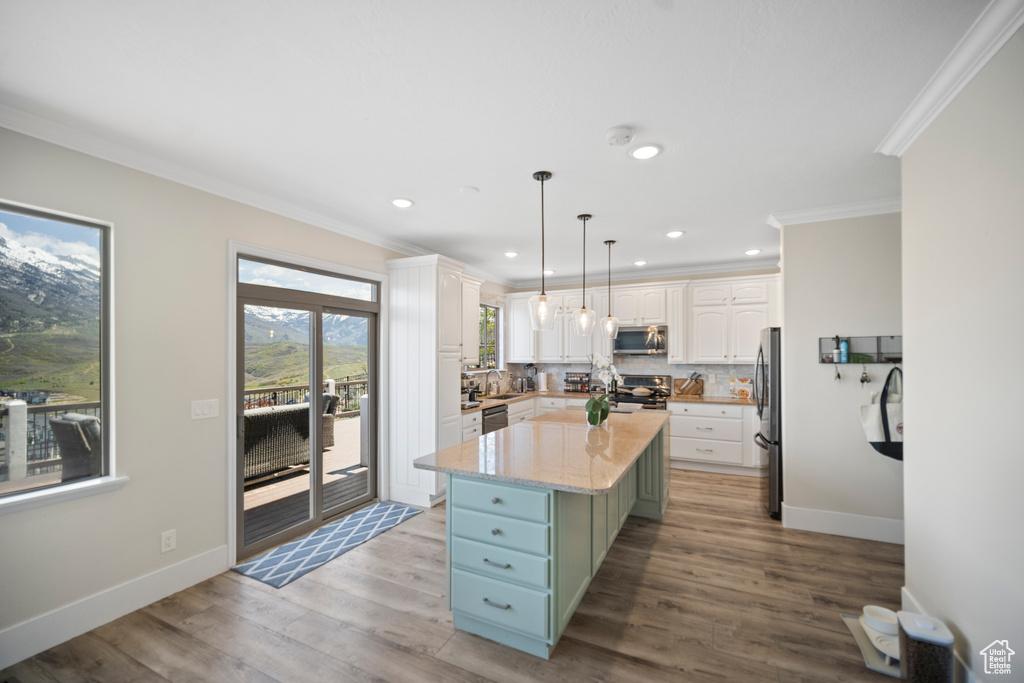 Kitchen with stainless steel appliances, white cabinetry, crown molding, backsplash, and recessed lighting