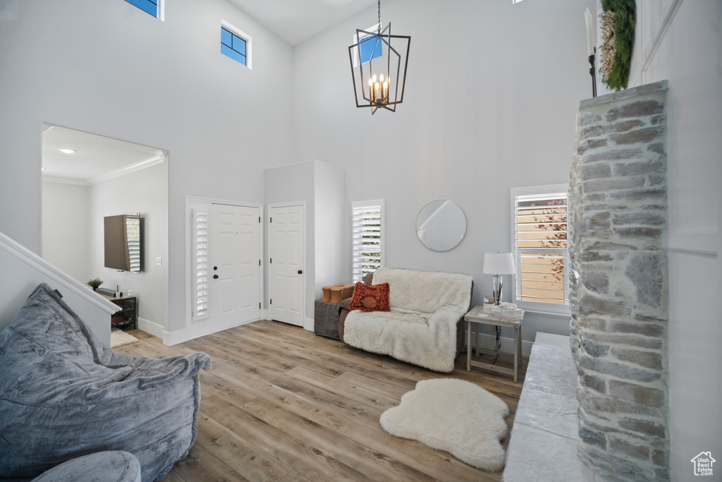 Living area featuring wood finished floors, a towering ceiling, plenty of natural light, a chandelier, and baseboards