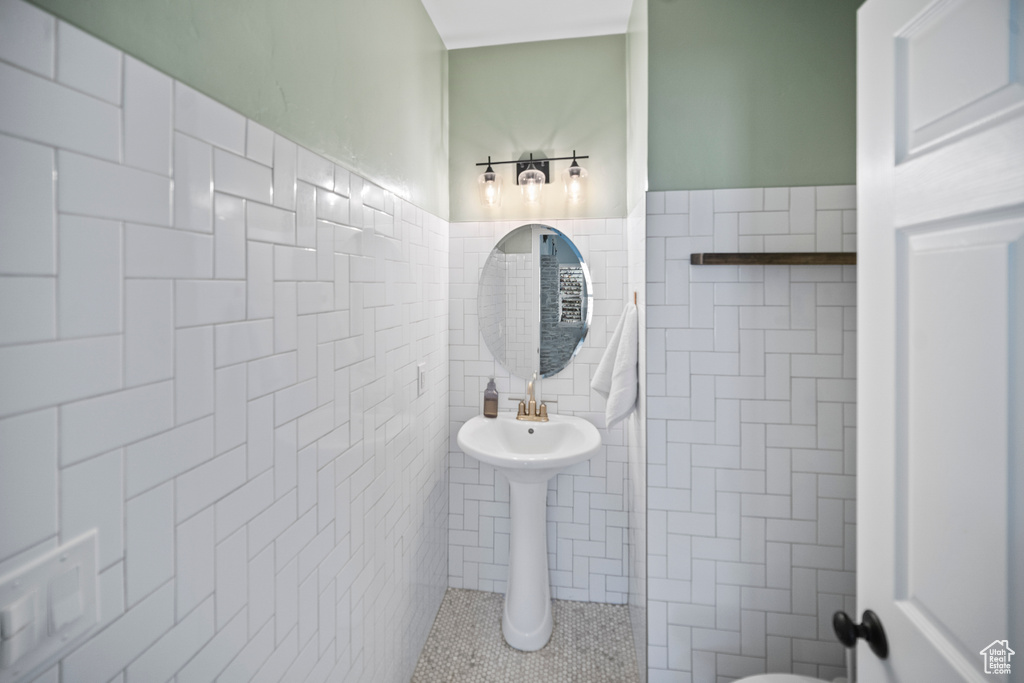 Half bath with tile walls, wainscoting, and tile patterned flooring