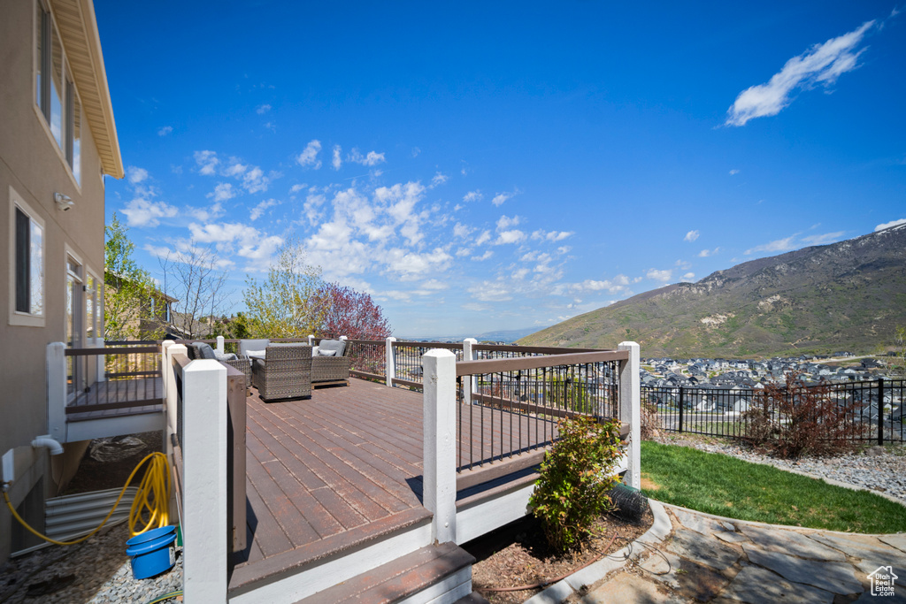 Wooden terrace featuring a mountain view, an outdoor living space, and fence