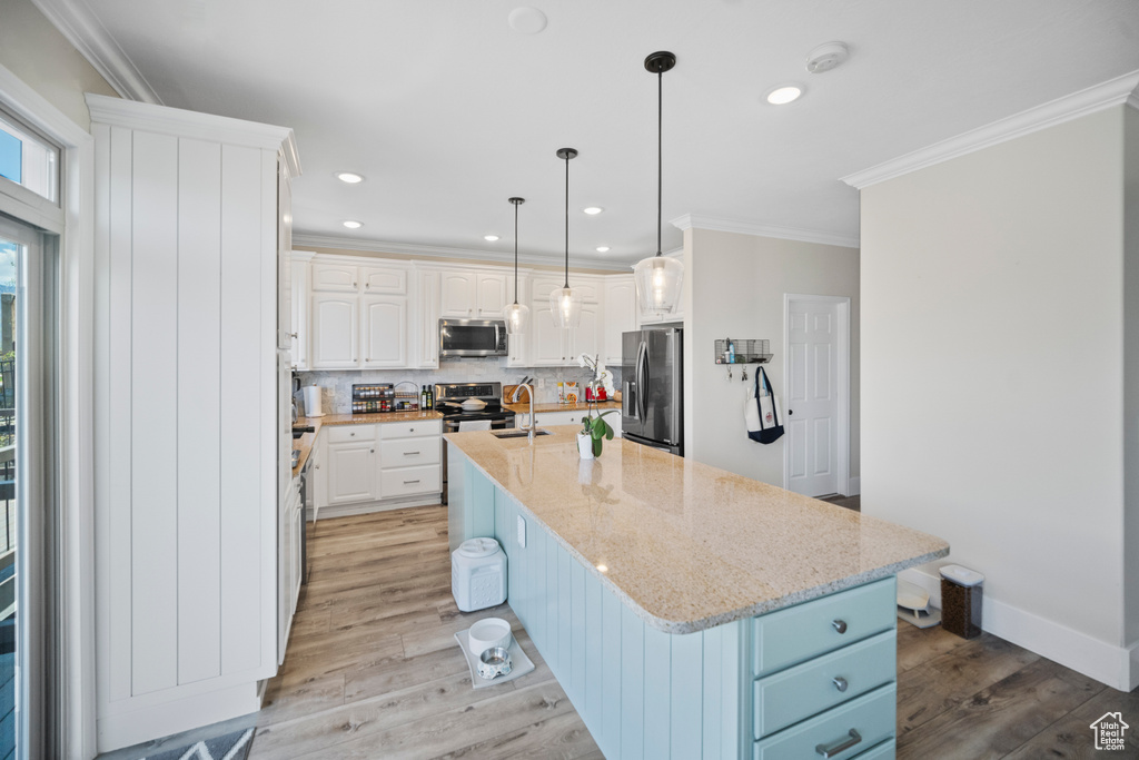Kitchen featuring stainless steel appliances, a sink, ornamental molding, backsplash, and white cabinets