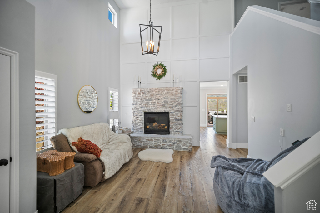 Living area with a high ceiling, wood finished floors, a chandelier, and a fireplace