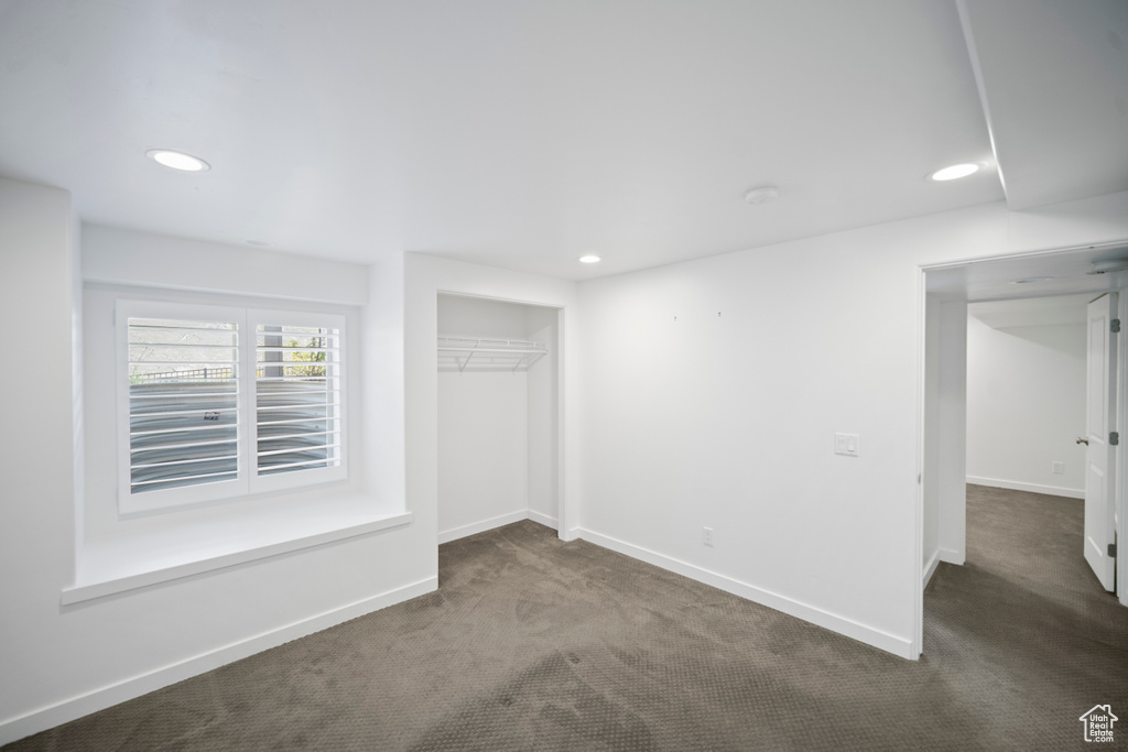 Unfurnished bedroom with dark colored carpet, baseboards, recessed lighting, and a closet