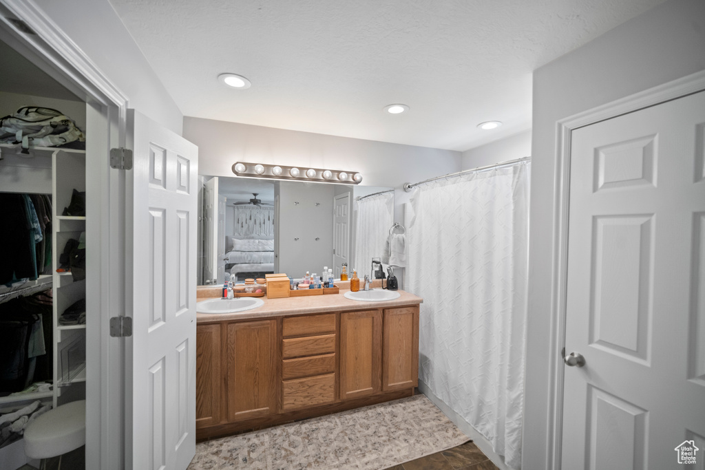 Ensuite bathroom featuring double vanity, a walk in closet, curtained shower, and recessed lighting