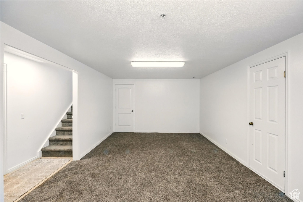 Finished basement featuring carpet flooring, stairway, a textured ceiling, and baseboards