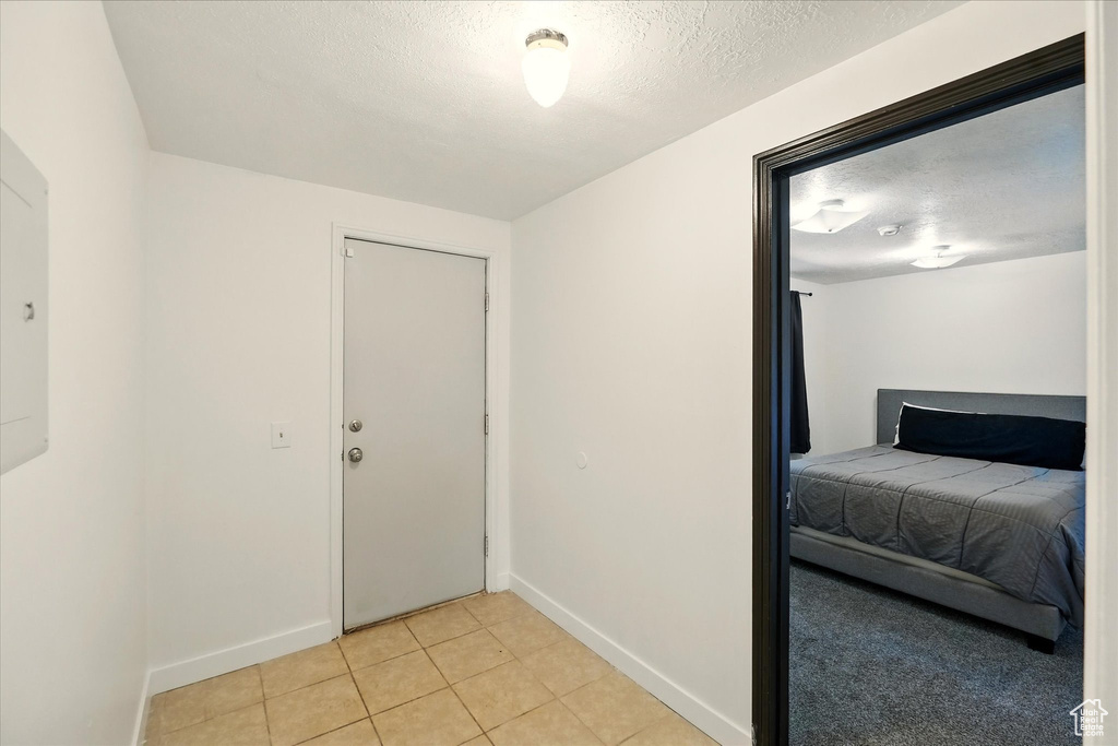 Foyer with baseboards, light tile patterned floors, and a textured ceiling